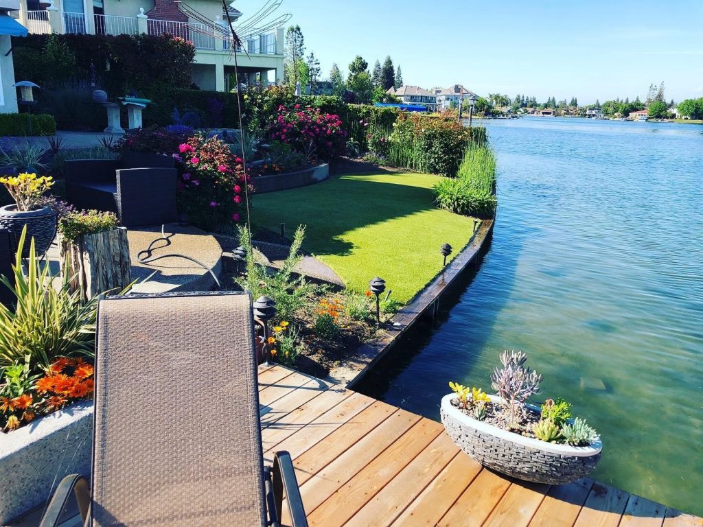A California backyard with artificial grass overlooking a lake.